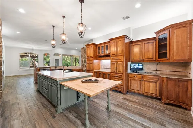 a kitchen with stainless steel appliances granite countertop wooden cabinets a stove a sink and a wooden floors