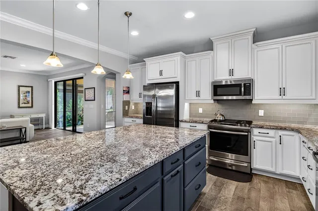 a kitchen with stainless steel appliances granite countertop a stove refrigerator and cabinets