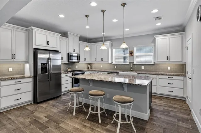 a kitchen with kitchen island granite countertop a sink and a refrigerator