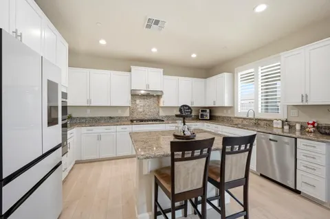 a kitchen with stainless steel appliances granite countertop a white cabinets and wooden floor