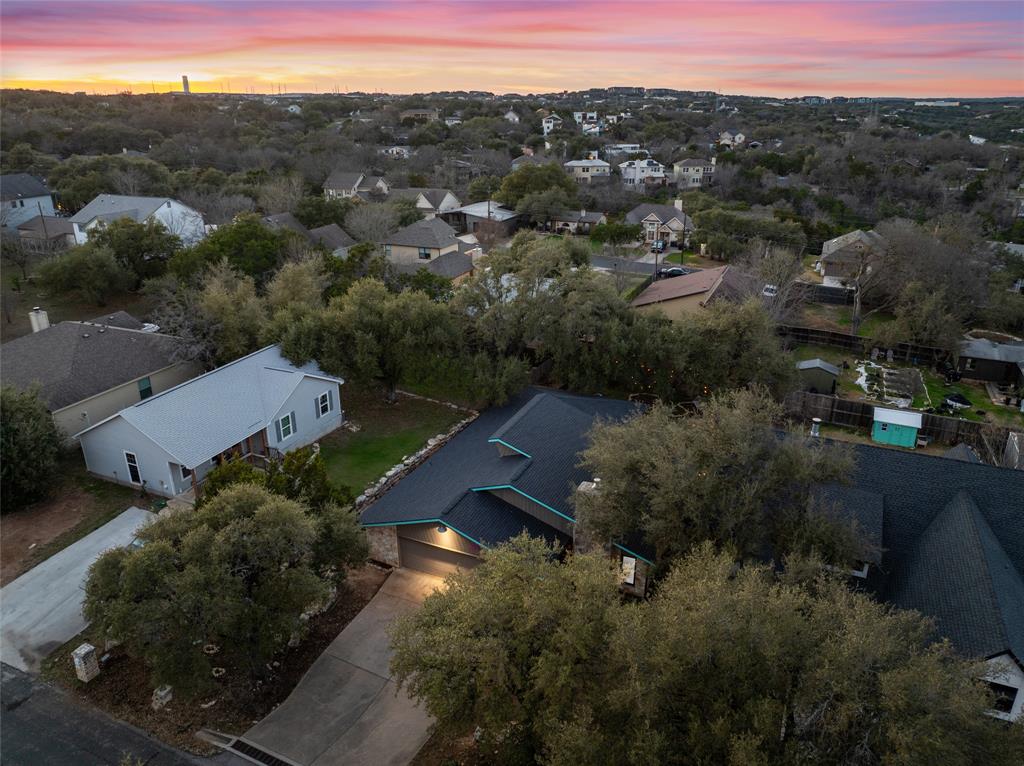 2210 Red Fox Road Austin, TX 78734 - Photo 2 of 40 An aerial perspective reveals the neighborhood nestled amidst verdant trees under a pastel sunset.