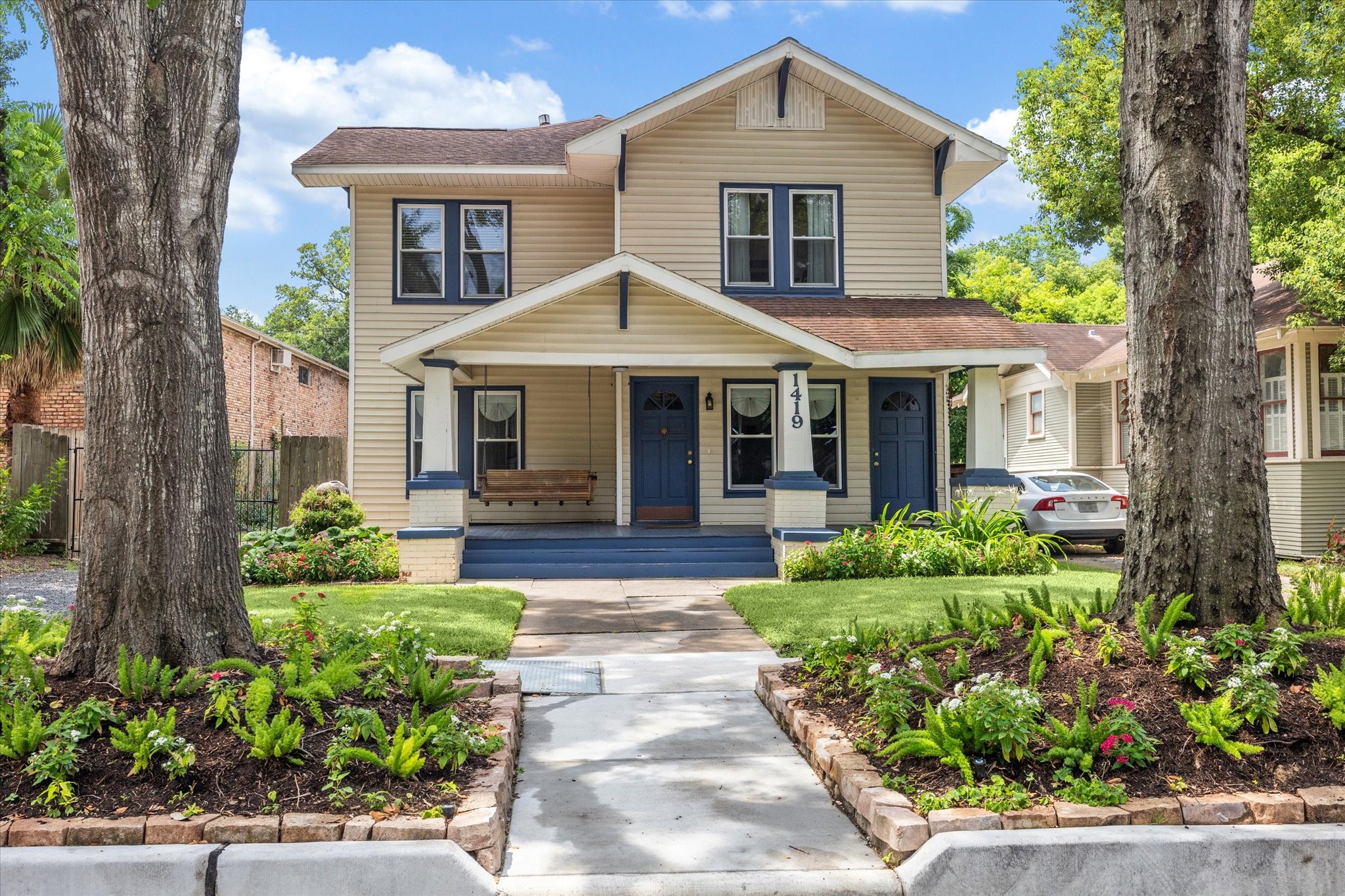 a front view of a house with a yard and potted plants
