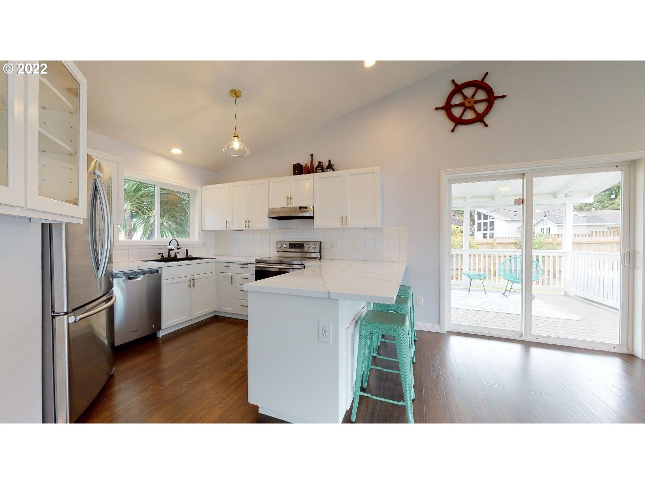 335 Mill Beach Road Brookings, OR 97415 - Photo 5 of 32 a open kitchen with stainless steel appliances kitchen island granite countertop a refrigerator a stove top oven a sink dishwasher and white cabinets with wooden floor