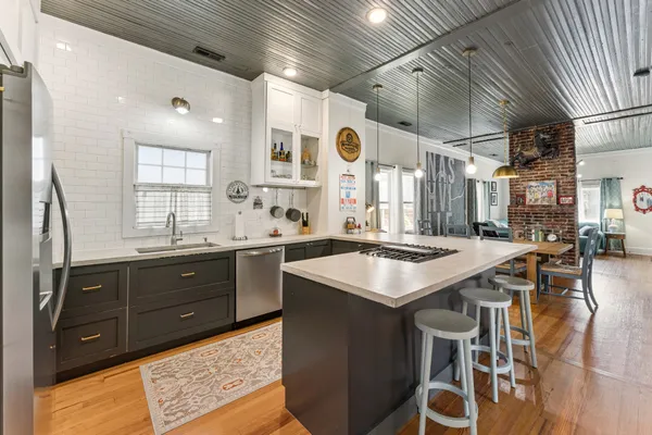 a kitchen with a stove a sink dishwasher and a dining table with wooden floor