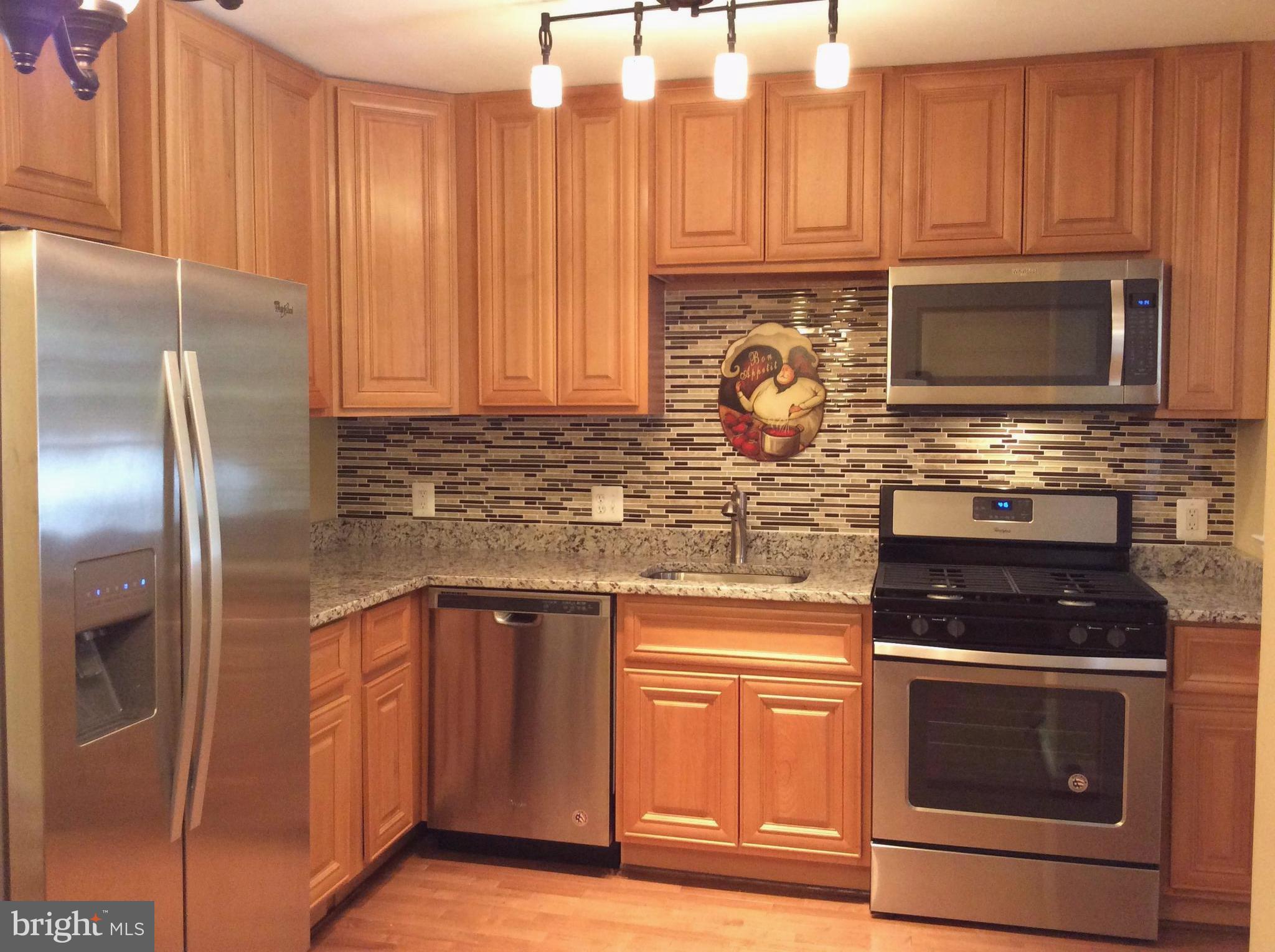 a kitchen with granite countertop stainless steel appliances wooden cabinets a stove top oven