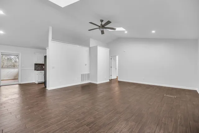 a view of an empty room with wooden floor and a ceiling fan