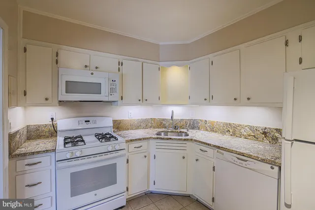 a kitchen with granite countertop white cabinets and white appliances