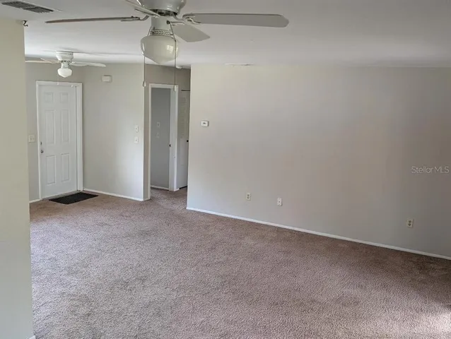 a view of an empty room with a chandelier fan