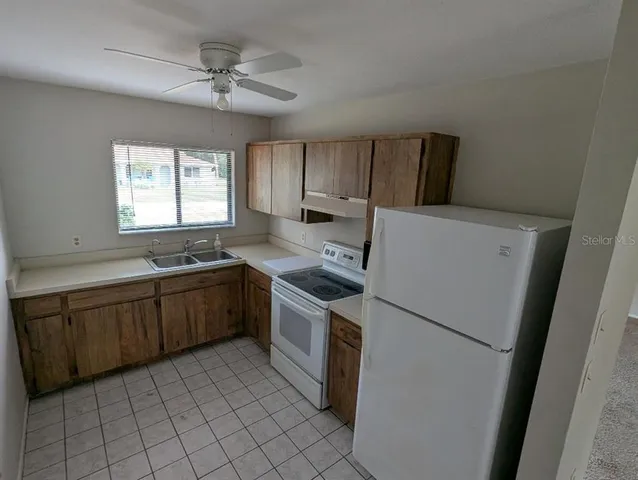 a kitchen with a sink a refrigerator a window and cabinets
