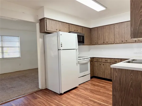 a kitchen with a refrigerator a stove and wooden floor
