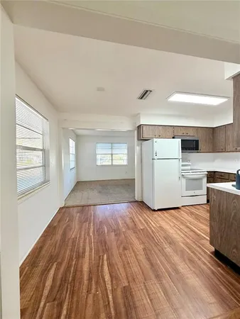 a view of empty room with kitchen and wooden floor
