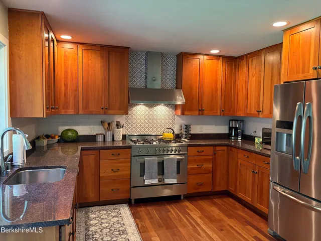 a kitchen with stainless steel appliances granite countertop a stove a sink dishwasher and cabinets with wooden floor