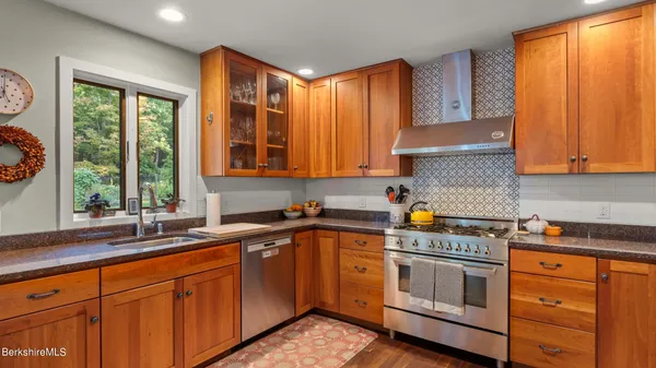 a kitchen with stainless steel appliances granite countertop a sink a stove cabinets and a window