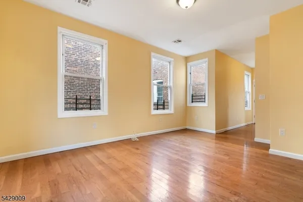 a view of an empty room with window and wooden floor