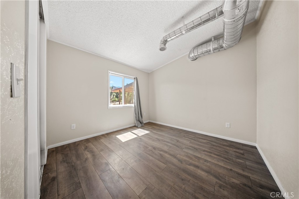 2033 Hollister Road Pinon Hills, CA 92372 - Photo 16 of 25 an empty room with wooden floor and windows