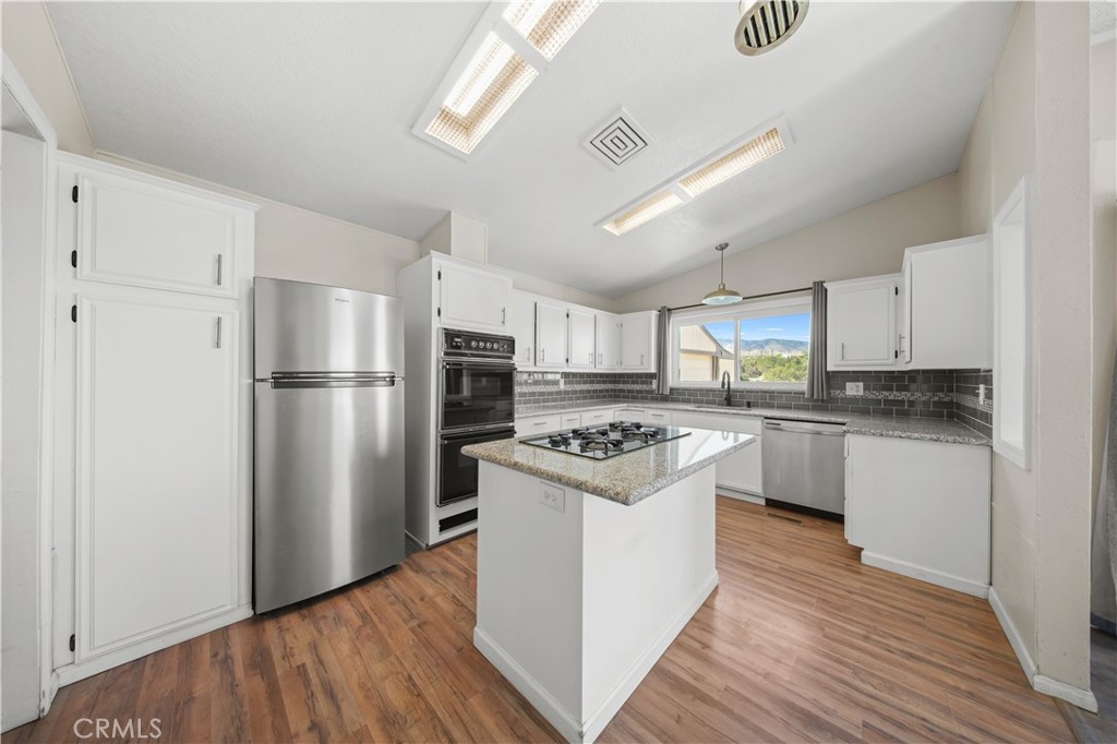 2033 Hollister Road Pinon Hills, CA 92372 - Photo 4 of 25 a kitchen with a refrigerator a sink dishwasher stove and white cabinets with wooden floor