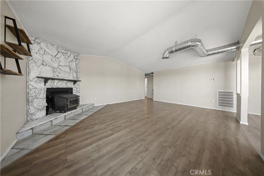 2033 Hollister Road Pinon Hills, CA 92372 - Photo 7 of 25 an empty room with wooden floor fireplace and windows