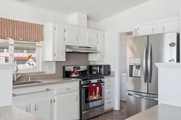 a kitchen with white cabinets and window