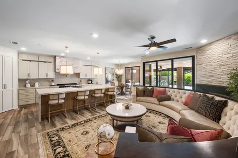 a living room with furniture a rug kitchen view and a large window