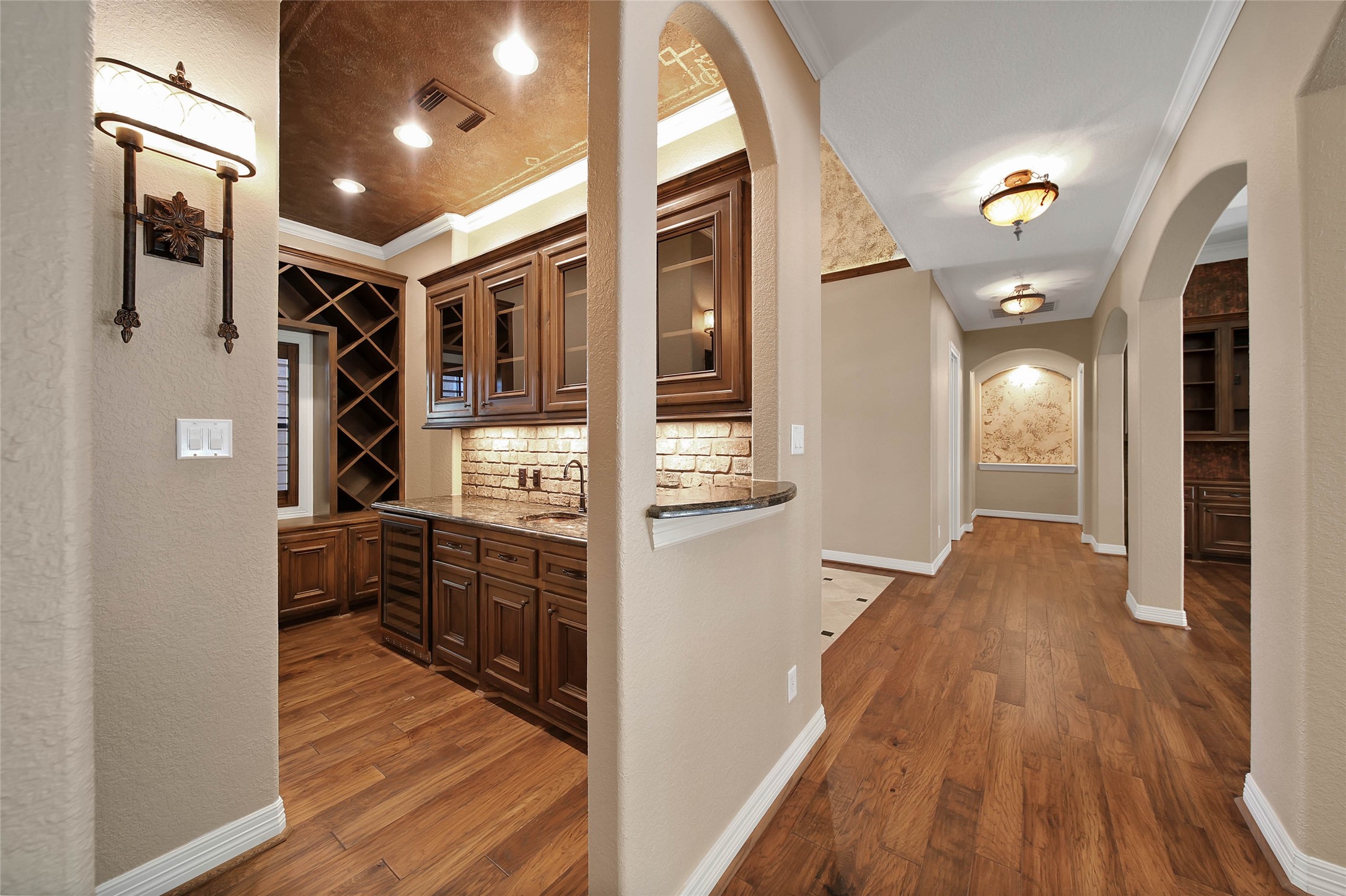 6803 Star Ledge Court Spring, TX 77389 - Photo 5 of 48 Wet bar with serving window, wine storage, cabinetry galore including glass-front upper cabinets, recessed lighting, granite countertop, sink, ice maker, and plenty of storage