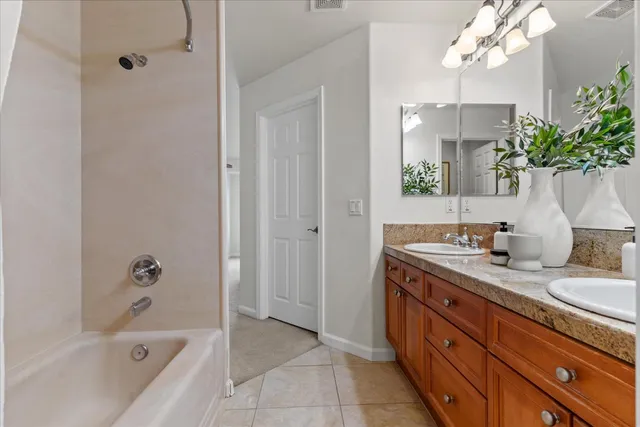 a bathroom with a granite countertop sink a mirror a bathtub and shower
