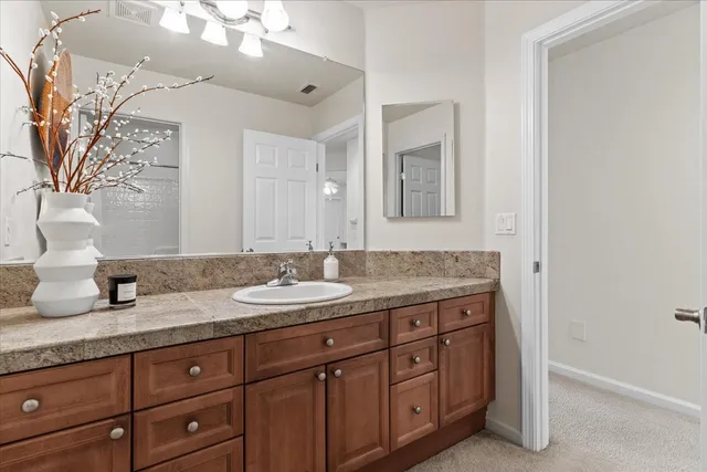 a bathroom with a granite countertop double vanity sink and mirror