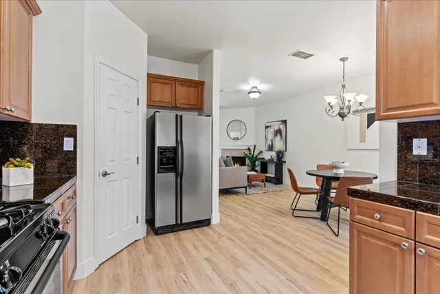 a dining room with chandelier fan and wooden floor