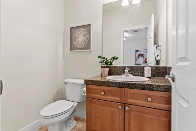 a bathroom with a granite countertop toilet sink and mirror