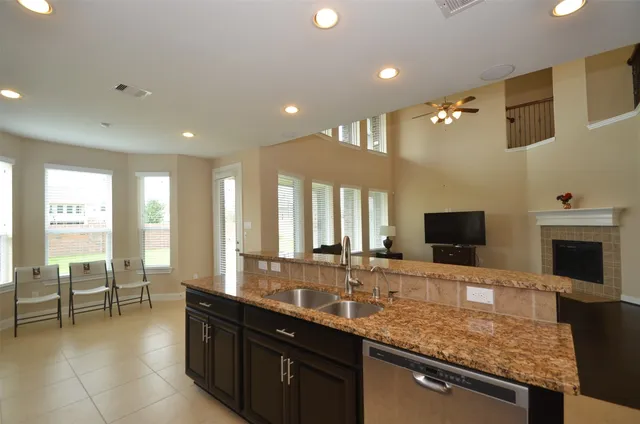 a large kitchen with kitchen island granite countertop a sink and a view of living room