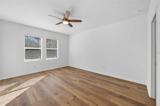 a view of empty room with wooden floor and fan