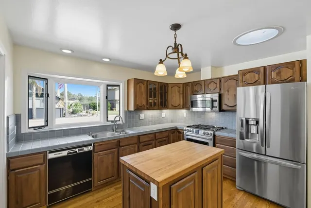 a kitchen with stainless steel appliances granite countertop stove a refrigerator and a sink with wooden floor