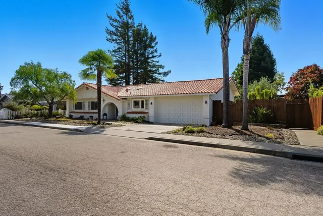 front view of a house with a yard and palm trees