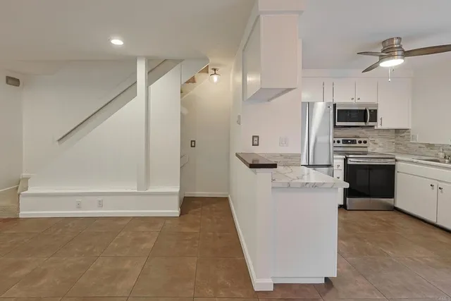 a living room with stainless steel appliances furniture a rug and a view of kitchen