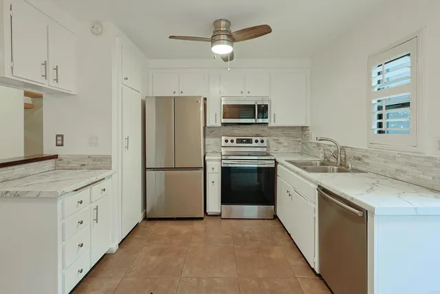 a kitchen with granite countertop a sink stove and refrigerator