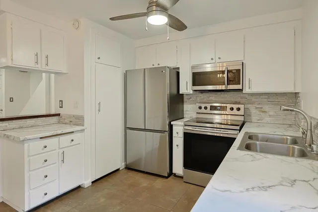 a kitchen with granite countertop a refrigerator stove and microwave