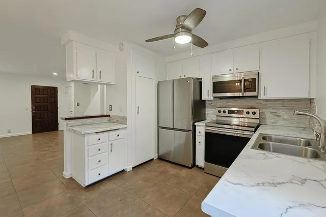 a kitchen with stainless steel appliances a stove a refrigerator a microwave a sink and white cabinets