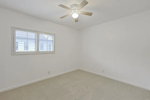an empty room with a window and a fan