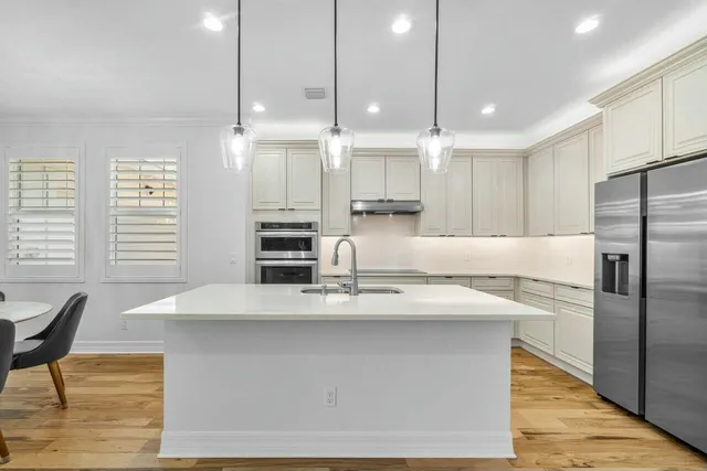 a large kitchen with kitchen island a large counter top space a sink stainless steel appliances and cabinets