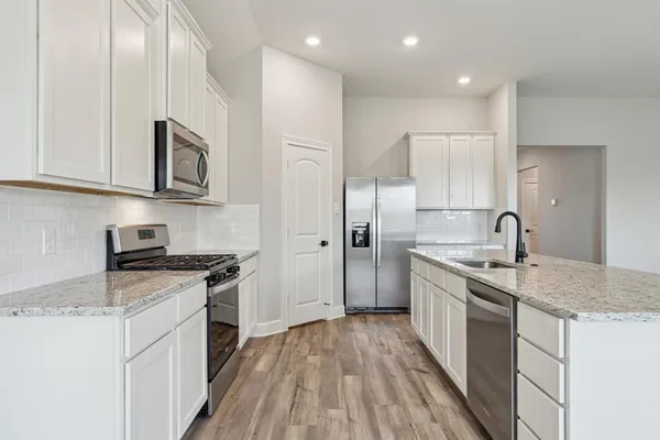 a kitchen with stainless steel appliances granite countertop a sink stove and refrigerator