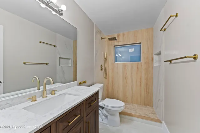 a bathroom with a granite countertop sink toilet and shower
