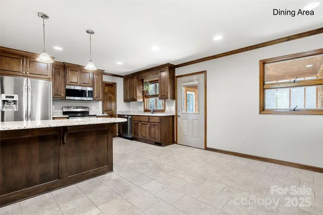 a kitchen with stainless steel appliances granite countertop a refrigerator a sink a stove top oven and a center island