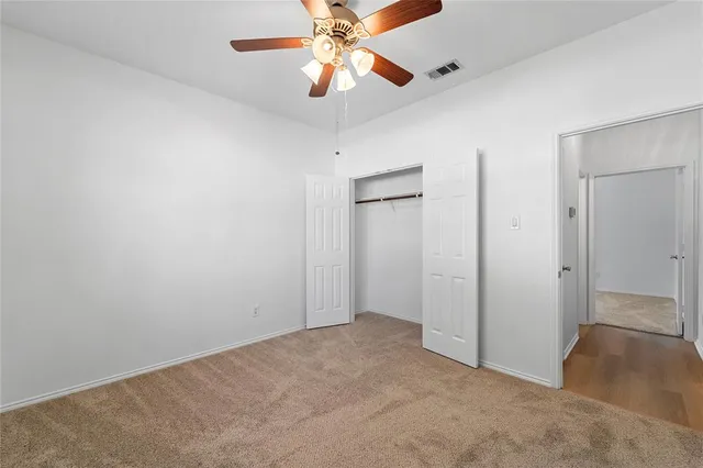 an empty room with closet and a chandelier fan