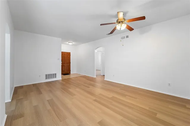 a view of empty room with wooden floor and ceiling fan