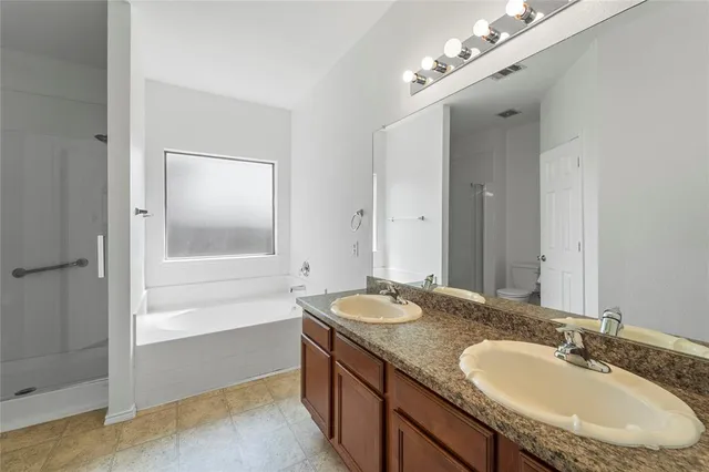 a bathroom with a granite countertop double vanity sink and a mirror