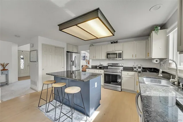 a kitchen with granite countertop a stove top oven cabinets and a refrigerator