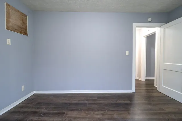 a view of an empty room with wooden floor and closet
