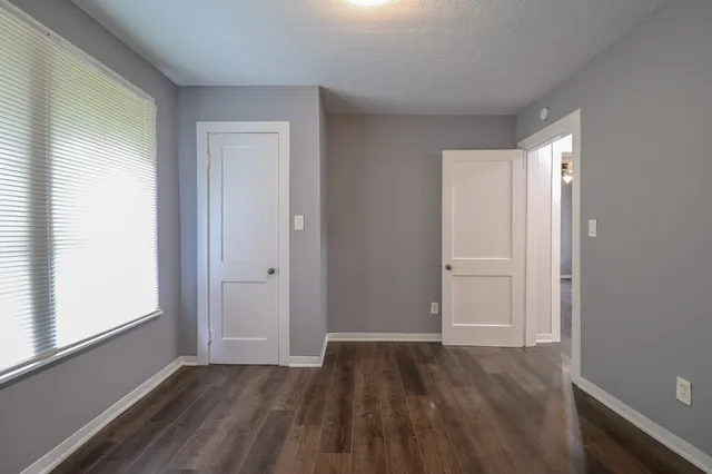 an empty room with wooden floor and windows