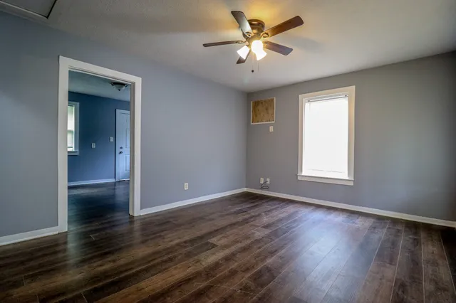 a view of an empty room with wooden floor and a window
