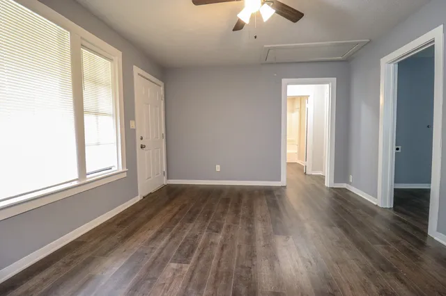 a view of an empty room with wooden floor and a window