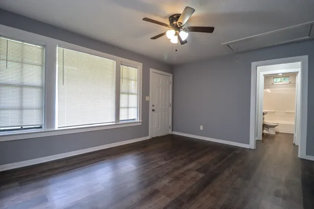 a view of an empty room with a window and wooden floor